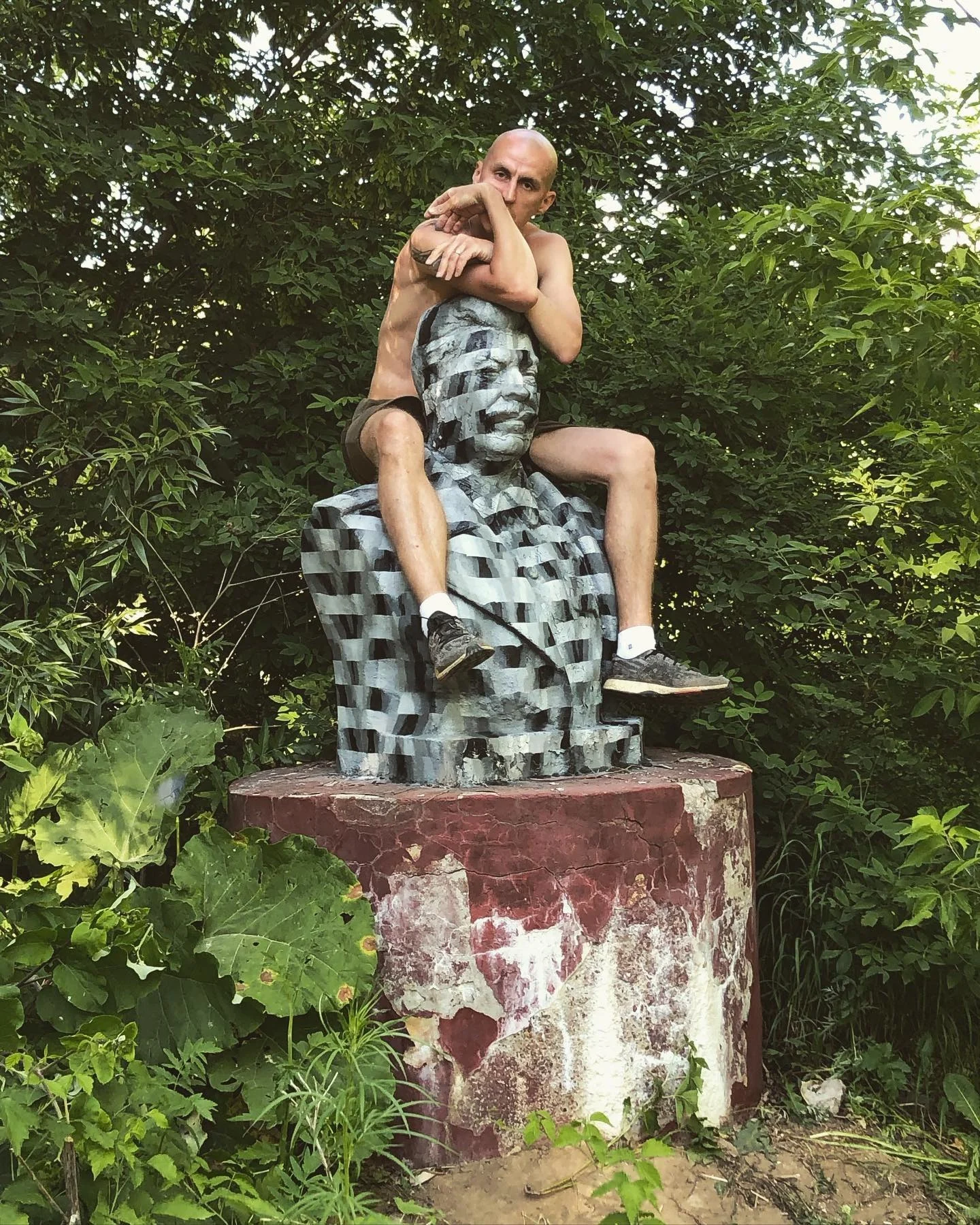 The artist sitting on a bust painted with an optical pattern